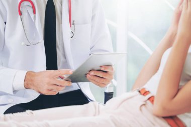 Erkek doktor konuşuyor ve Bayan hasta hastane ofisinde inceleyerek. Sağlık ve tıbbi hizmet.