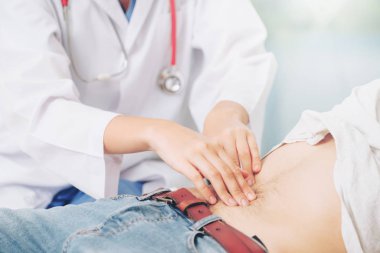 Kadın doktor konuşuyor ve erkek hasta hastane ofisinde inceleyerek. Sağlık ve tıbbi hizmet.