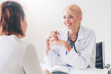 Kadın doktor konuşuyor ve Bayan hasta hastane ofisinde inceleyerek. Sağlık ve tıbbi hizmet.