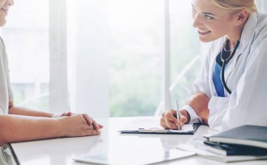 Kadın doktor görüşmeler yazarken bayan hasta için hastanın sağlık kaydının hastane ofiste. Sağlık ve tıbbi hizmet.