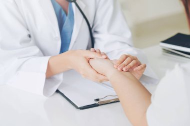 Kadın doktor hastane ofiste bayan hasta için eller tarafından hasta darbe incelenirken konuşuyor. Sağlık ve tıbbi hizmet.
