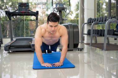 Fitness merkezinde itme yaparken vücut geliştirmeci genç adam. Sağlıklı yaşam tarzı ve vücut geliştirme kavramı.