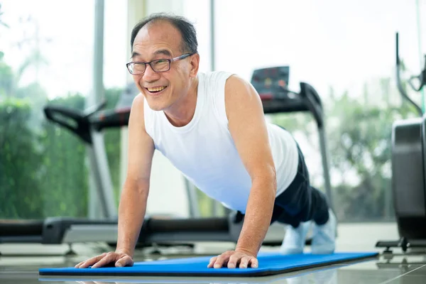 Senior man push up in fitness gym. Mature healthy lifestyle.