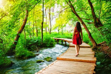 Göller ve şelale peyzaj Plitvice Gölleri Milli Parkı, Unesco Dünya Mirası ve ünlü seyahat hedef Hırvatistan ile ahşap yol iz üzerinde yürüyen kadın gezgin.