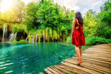 Göller ve şelale peyzaj Plitvice Gölleri Milli Parkı, Unesco Dünya Mirası ve ünlü seyahat hedef Hırvatistan ile ahşap yol iz üzerinde yürüyen kadın gezgin.