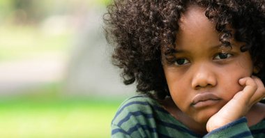 Mutsuz küçük Afro-Amerikan çocuk parkta oturan sıkılmış. Boy gösteren negatif duygu. Çocuk sorun kavramı.