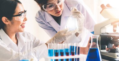 Laboratuvarda deney tüpü ve bilimsel aletlerdeki biyokimya örneklerini incelerken laboratuvar önlüğü giyen bir grup bilim adamı. Bilim teknolojisi araştırma ve geliştirme konsepti.