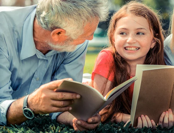 幸福的家庭一起读书 躺在公共公园的绿草上 在户外花园里和父亲一起学习的小女孩 教育和家庭生活方式 — 图库照片