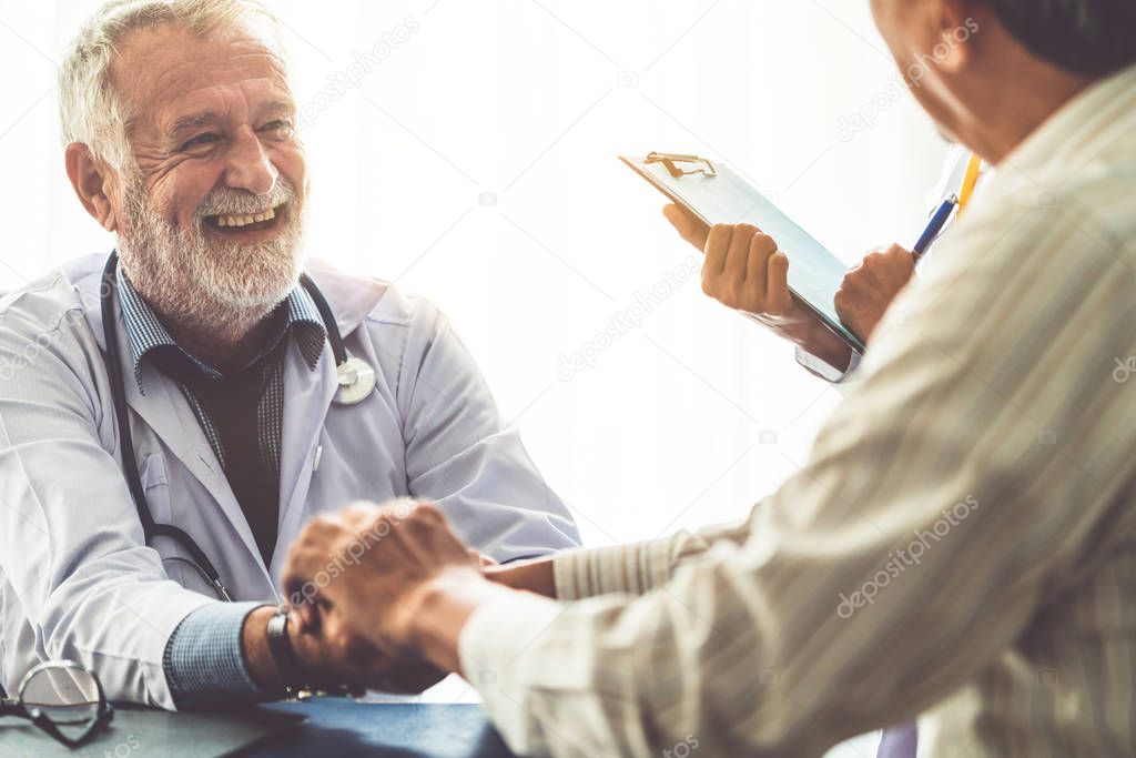 Senior male doctor talking to elder man patient in the hospital office. Medical healthcare and doctor staff service concept.