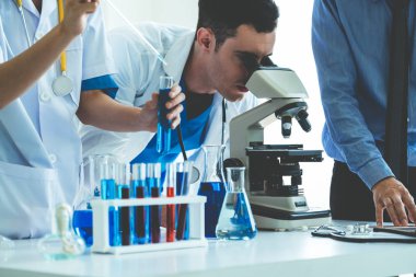 Laboratuvarda deney tüpü ve bilimsel aletlerdeki biyokimya örneklerini incelerken laboratuvar önlüğü giyen bir grup bilim adamı. Bilim teknolojisi araştırma ve geliştirme konsepti.