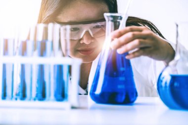 Laboratuvarda çalışan ve deney tüpündeki biyokimya örneklerini inceleyen kadın bilim adamı. Bilim teknolojisi araştırma ve geliştirme konsepti.