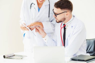 Doktor hastane ofis dizüstü bilgisayar masanın üzerinde başka bir doktor hasta sağlık hakkında tartışma ile çalışma.
