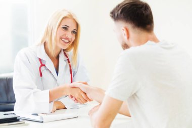 Kadın doktor hastane office odasında erkek hasta ile karşılıklı yapıyor. Sağlık ve Medikal hizmet meslekleri.