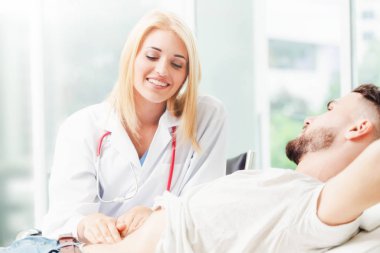 Kadın doktor konuşuyor ve erkek hasta hastane ofisinde inceleyerek. Sağlık ve tıbbi hizmet.