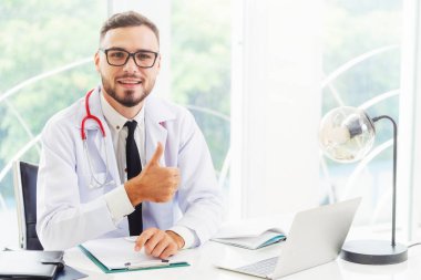 Doktor hastanede ofis masasında çalışırken başparmak göstermek yukarıya. Tıbbi ve sağlık kavramı.