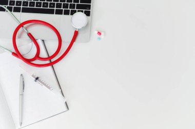 Tıbbi sağlık arka düz kopya alanı ile nesneleri yatıyordu. Doktor stetoskop, tıp, dizüstü bilgisayar ve dizüstü üzerinde beyaz Ofis masaları.
