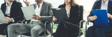 İş kadınları ve iş adamları iş görüşmesi için koltuklarda beklerken CV dosyasına devam ediyorlar. Şirket işi ve insan kaynakları kavramı.