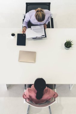 İş başvurusu ve iş anlaşması için ofis masasında toplanan iki genç iş kadını. İşe alım ve insan kaynakları kavramı.