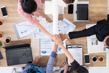 İş adamları ve iş kadınları, takım çalışması, destek ve iş birliğini gösteren çok kültürlü ofis odasındaki grup toplantılarında el ele tutuşuyorlar. Çeşitlilik işyeri ve kurumsal insanların çalışma konsepti.