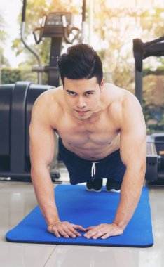 Fitness merkezinde itme yaparken vücut geliştirmeci genç adam. Sağlıklı yaşam tarzı ve vücut geliştirme kavramı.