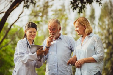 Üst düzey iki adam ve kadın genç hemşire veya parkta caregiver söz. Olgun insanlar sağlık ve tıbbi personel hizmet anlayışı.
