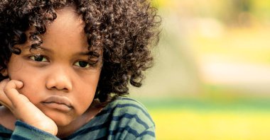 Mutsuz küçük Afro-Amerikan çocuk parkta oturan sıkılmış. Boy gösteren negatif duygu. Çocuk sorun kavramı.
