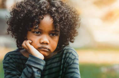 Mutsuz küçük Afro-Amerikan çocuk parkta oturan sıkılmış. Boy gösteren negatif duygu. Çocuk sorun kavramı.