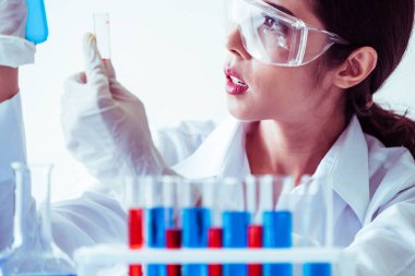 Laboratuvarda çalışan ve deney tüpündeki biyokimya örneklerini inceleyen kadın bilim adamı. Bilim teknolojisi araştırma ve geliştirme konsepti.
