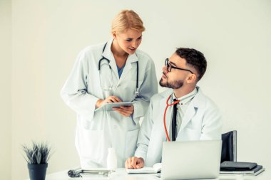 Doktor hastane ofis dizüstü bilgisayar masanın üzerinde başka bir doktor hasta sağlık hakkında tartışma ile çalışma.