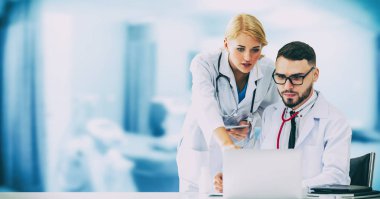 Doktor hastanede başka bir doktor ile bir tartışma yaparken ofiste dizüstü bilgisayarla çalışma. Tıbbi sağlık ve doktor hizmeti.