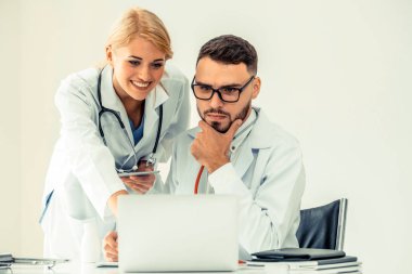 Doktor hastane ofis dizüstü bilgisayar masanın üzerinde başka bir doktor hasta sağlık hakkında tartışma ile çalışma.