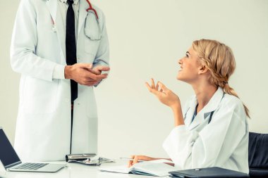 Genç kadın doktor hastane ofisindeki masanın ayakta başka bir erkek doktor ile konuşurken konuşmayı. Tıbbi sağlık profesyonel takım kavramı.