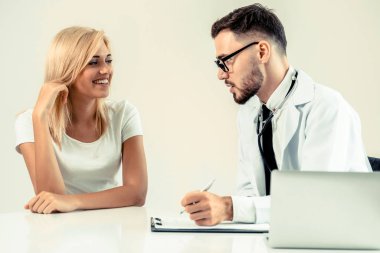 Hastanın sağlık kaydının tablosundaki tarih yazarken hastane ofiste bayan hasta için erkek doktor konuşuyor. Sağlık ve tıbbi hizmet.