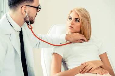 Erkek doktor konuşuyor ve Bayan hasta hastane ofisinde inceleyerek. Sağlık ve tıbbi hizmet.