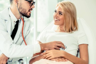 Erkek doktor konuşuyor ve Bayan hasta hastane ofisinde inceleyerek. Sağlık ve tıbbi hizmet.