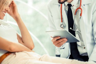 Erkek doktor konuşuyor ve Bayan hasta hastane ofisinde inceleyerek. Sağlık ve tıbbi hizmet.