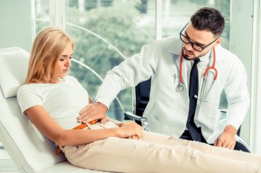 Erkek doktor konuşuyor ve Bayan hasta hastane ofisinde inceleyerek. Sağlık ve tıbbi hizmet.