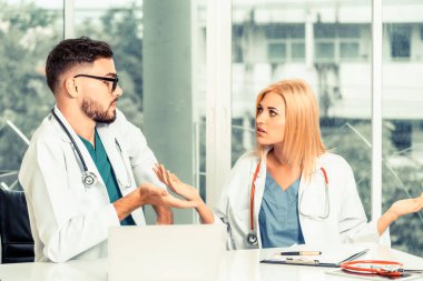 Genç kadın doktor hastane ofiste onun yanında oturan erkek doktor için konuşurken çalışıyor. Tıbbi hizmet ve sağlık kavramı.