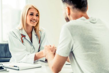 Kadın doktor hastane office odasında erkek hasta ile karşılıklı yapıyor. Sağlık ve Medikal hizmet meslekleri.