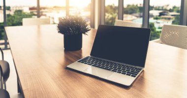 Ofisteki çalışma masasında kapağı açık dizüstü bilgisayar.