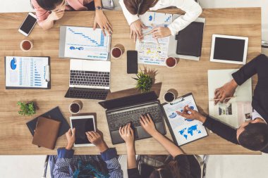 Modern ofisteki iş adamları ve iş kadınlarıyla grup toplantısındaki iş adamlarının en üst düzey görüşü, masada dizüstü bilgisayar, kahve ve belge ile. Şirket ortaklığı konsepti..