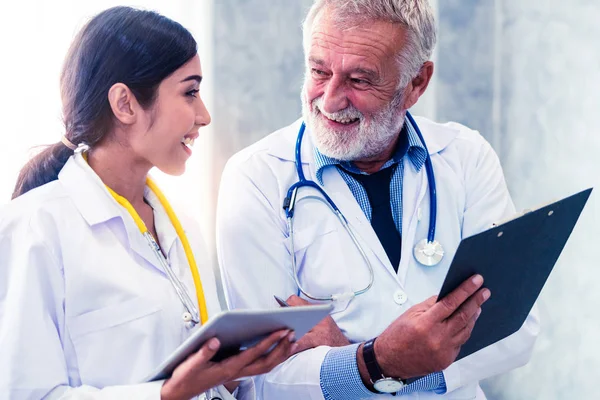 Senior Male Doctor Using Tablet Computer While Discussing Another Doctor — Stock Photo, Image