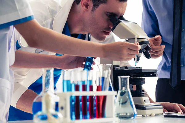 Group of scientists wearing lab coat working in laboratory while examining biochemistry sample in test tube and scientific instruments. Science technology research and development study concept.