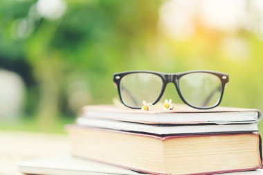 Yumuşak odak retro tarzı kitap ve göz gözlük doğa arka plan ile. Okuma ve eğitim kavramı.