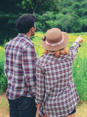 Mutlu çift tepelerde yeşil çim alandaki romantik bir yürüyüşe çık. Seyahat ve balayı konsepti.