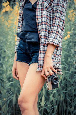 Genç kadın retro tarzı kamera açık doğa manzara modunda yaz aylarında seyahat ederken onun elinde tutan.