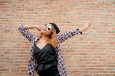 Tuğla duvar şehirdeki sokak karşı duran mutlu genç hipster kadın.