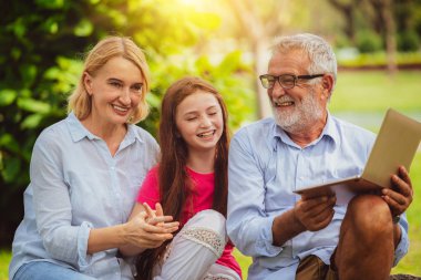 Mutlu aile dizüstü bilgisayar birlikte bahçe parkta yaz aylarında kullanma.. Çocuk eğitim ve aile etkinlikleri kavramı.