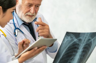 Üst düzey erkek doktor röntgen filmi ile başka bir Doktor hastanede çalışırken hastanın göğüs yaralanmaları bakarak. Tıbbi sağlık personeli ve doktor hizmeti.