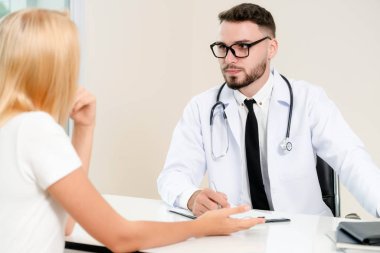 Erkek doktor hastane ofiste bayan hasta konuşuyor. Sağlık ve tıbbi hizmet.